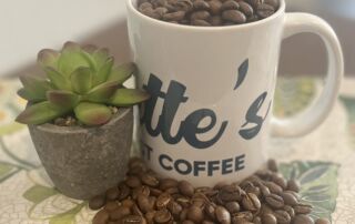 everettes-coffee-beans-mug-with-succulent-lifestyle-shot.png Everette’s Fresh Roast Coffee mug filled with whole coffee beans next to a small green succulent on a patterned table.