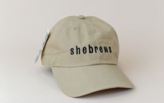 Tan SheBrews embroidered hat with curved brim and black stitching
