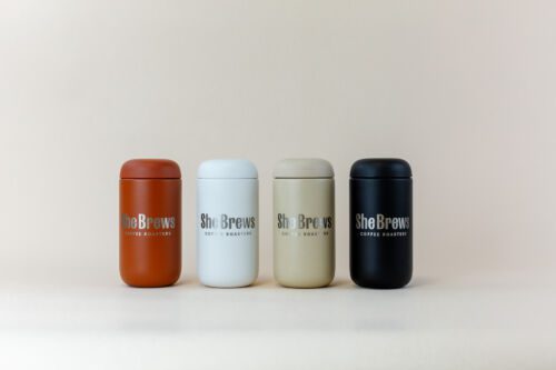 Four She Brews Coffee Roasters canisters in terracotta, white, tan, and black