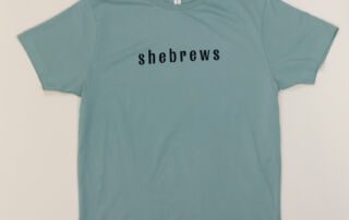 Front of teal She Brews t-shirt with minimalist “shebrews” text