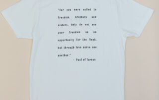 Back of white She Brews t-shirt featuring a Paul of Tarsus quote in black print
