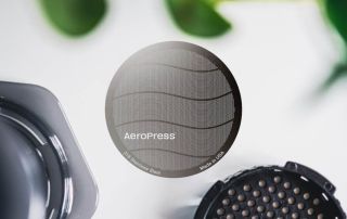 aeropress-metal-filter-reusable-unsung-roasters.jpg Reusable metal AeroPress coffee filter with wave pattern design.
