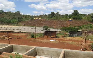 Overview of a coffee processing station in Ethiopia featuring raised beds and fermentation tanks.
